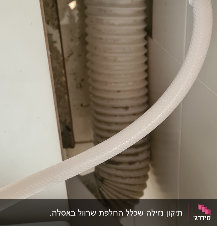צינור מים לבן וברז מתכת ליד צינור גמיש